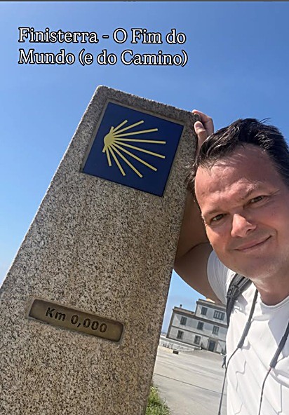 George Marmelstein ao lado do marco Km 0,000 em Finisterre, com a concha amarela do Caminho de Santiago