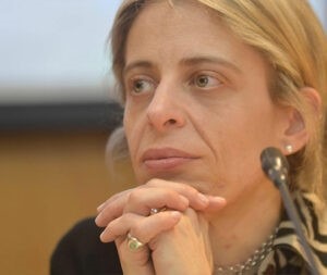 Mafalda Miranda Barbosa em um evento, pensativa, com o queixo apoiado nas mãos entrelaçadas diante de um microfone