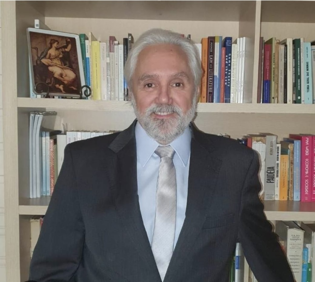 José Eduardo de Resende Chaves Júnior, de terno escuro e gravata clara, diante de uma estante de livros de direito e filosofia